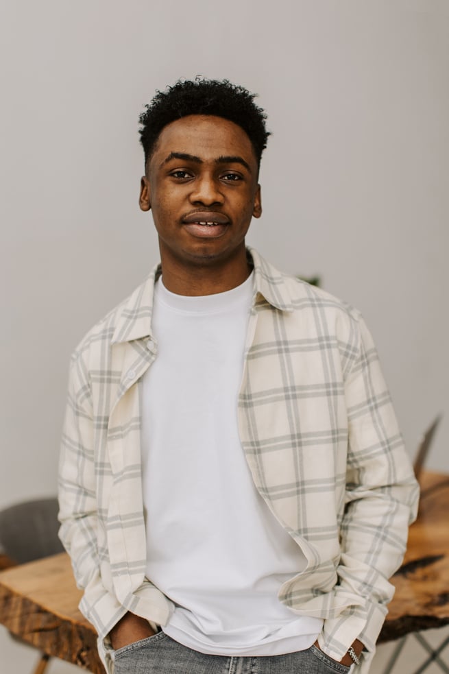 a person in a plaid standing in front of a gray background